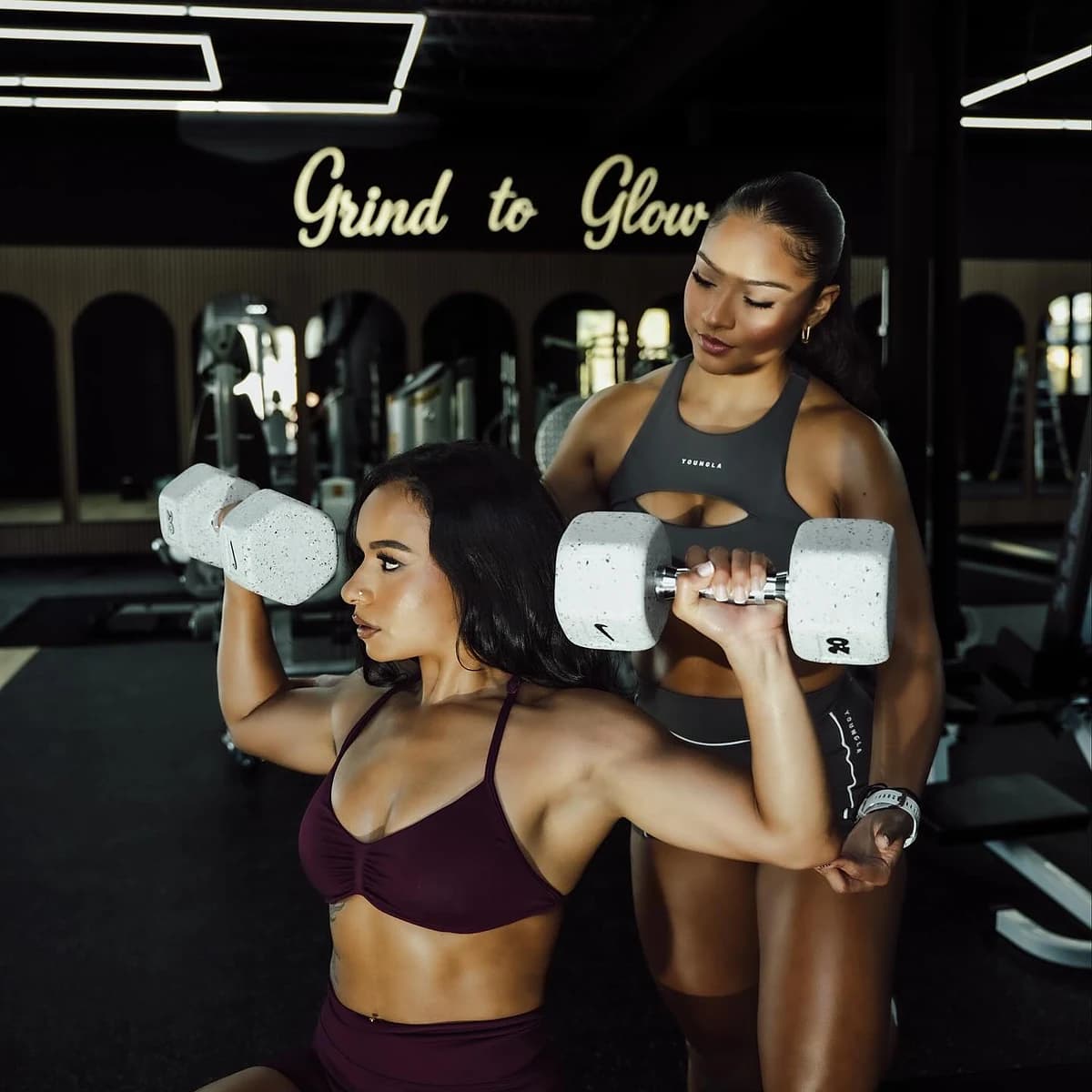Trainer spotting a seated dumbbell shoulder press